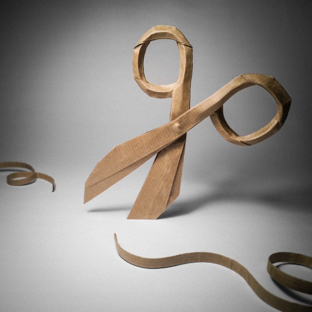 Origami of a pair of scissors cutting a ribbon.